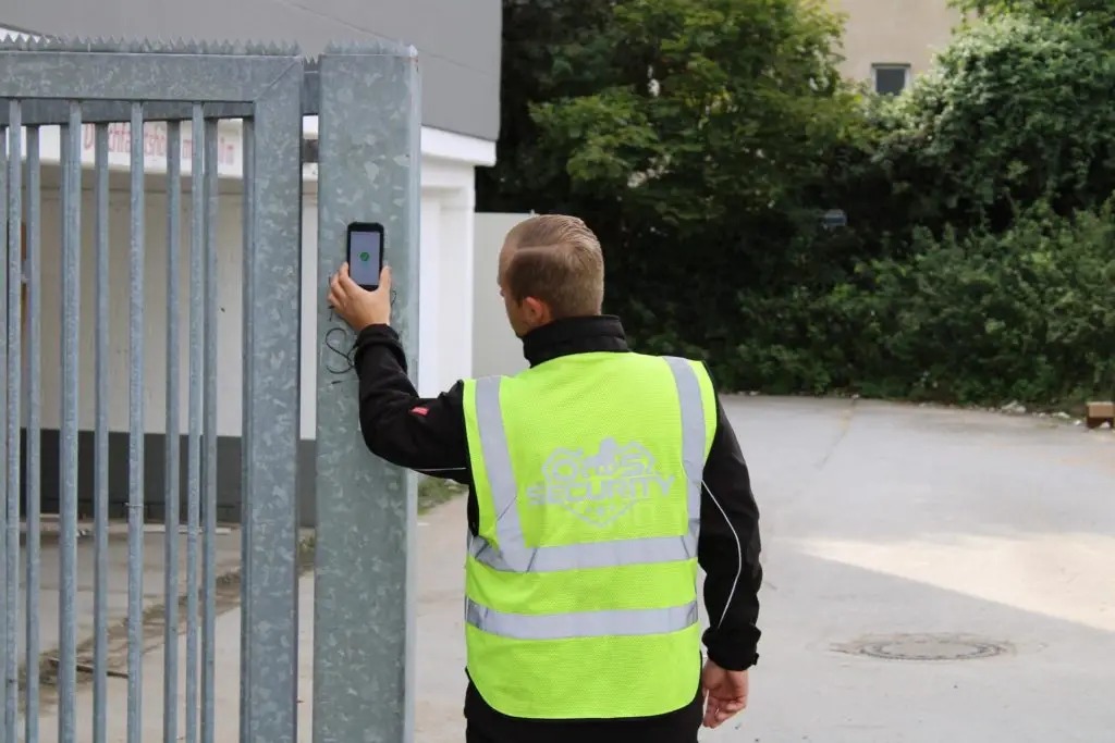 Sicherheitsmitarbeiter bei der Kontrolle eines Objekts, mit Prüfgerät am Tor